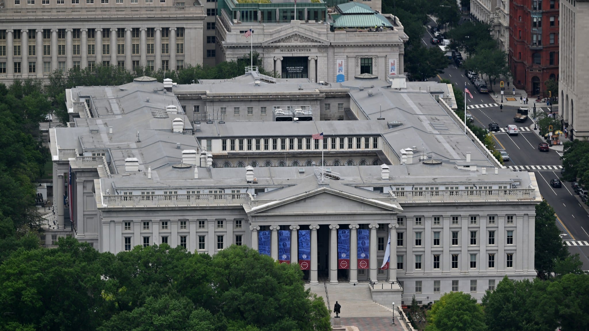 Aerial view of the US Treasury Department building in Washington, DC, with blue banners hanging between its columns.