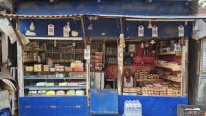 A small sweet shop in North 24 Parganas, West Bengal, with several QR code payment placards hanging along its front and a shopkeeper behind the counter.